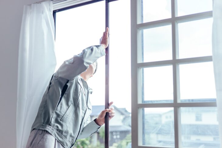 窓サッシを確認するリフォーム作業着の男性