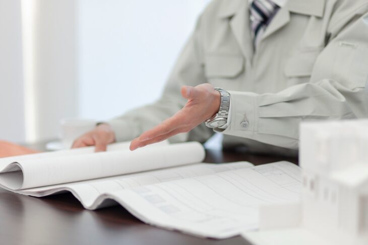 家の図面に手をかざすリフォームスタッフ